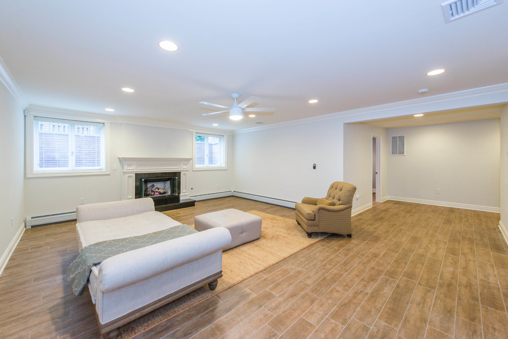 Example of a mid-sized classic walk-out porcelain tile basement design in New York with white walls, a standard fireplace and a wood fireplace surround