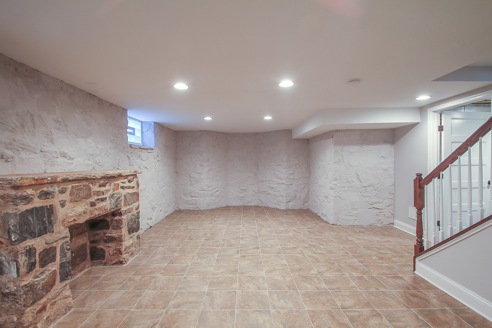 Basement - mid-sized contemporary underground ceramic tile basement idea in Baltimore with gray walls, a standard fireplace and a stone fireplace