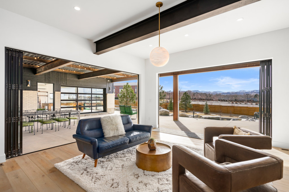 Modern walk-out basement in Denver with a home bar, white walls, light hardwood flooring and exposed beams.