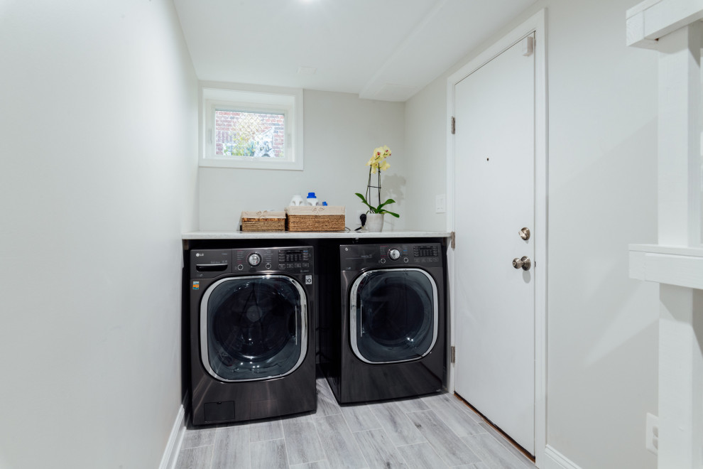 This is an example of a medium sized traditional utility room in Other with white walls, light hardwood flooring and grey floors.