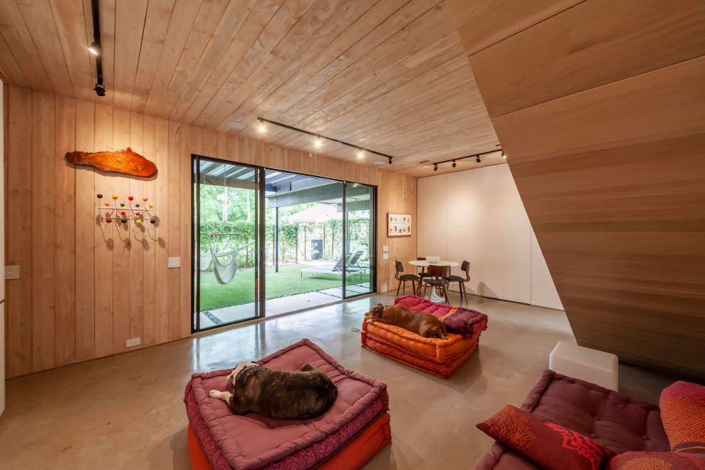 Idées déco pour un grand sous-sol moderne donnant sur l'extérieur avec un mur marron, sol en béton ciré, un sol gris, un plafond en bois et du lambris.