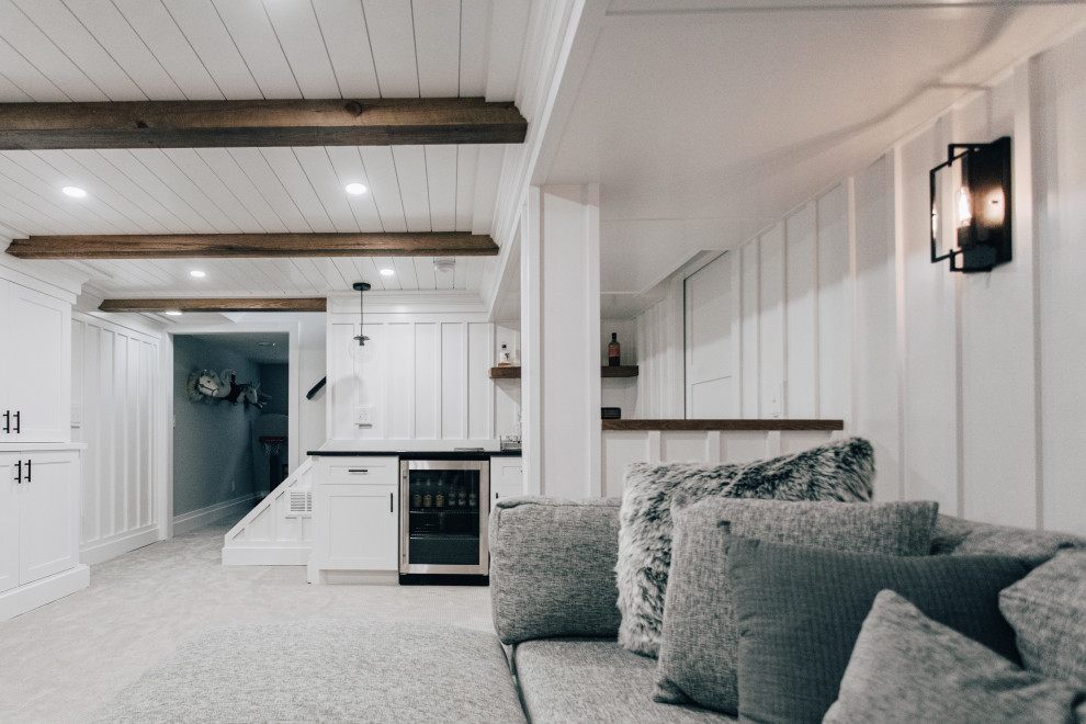 Bild på en mellanstor lantlig källare utan fönster, med en hemmabar, vita väggar, heltäckningsmatta och grått golv