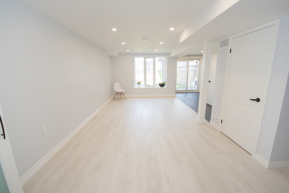 Inspiration for a mid-sized contemporary walk-out laminate floor and white floor basement remodel in Toronto with white walls and no fireplace