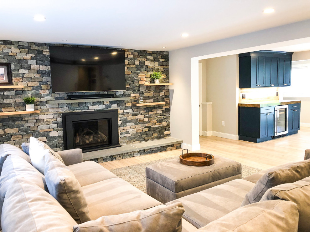 Example of a huge transitional walk-out light wood floor and brown floor basement design in Boston with gray walls, a standard fireplace and a stone fireplace