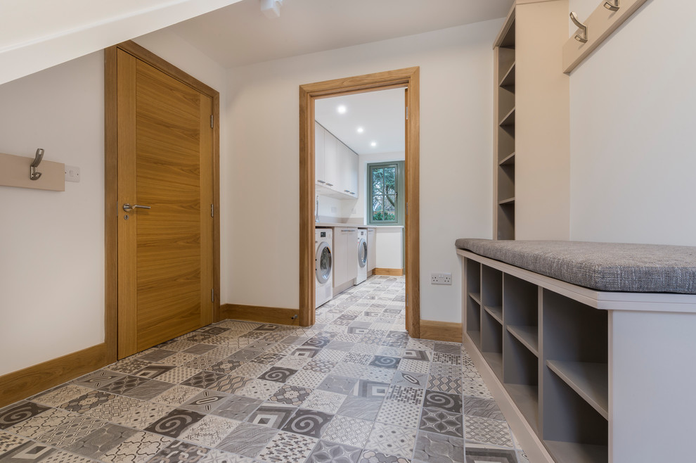 Diseño de sótano con puerta contemporáneo de tamaño medio con paredes blancas, suelo de baldosas de porcelana y suelo gris