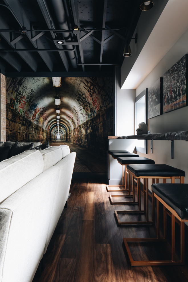 На фото: подземный подвал среднего размера с домашним баром, серыми стенами, полом из винила, стандартным камином, фасадом камина из плитки и коричневым полом