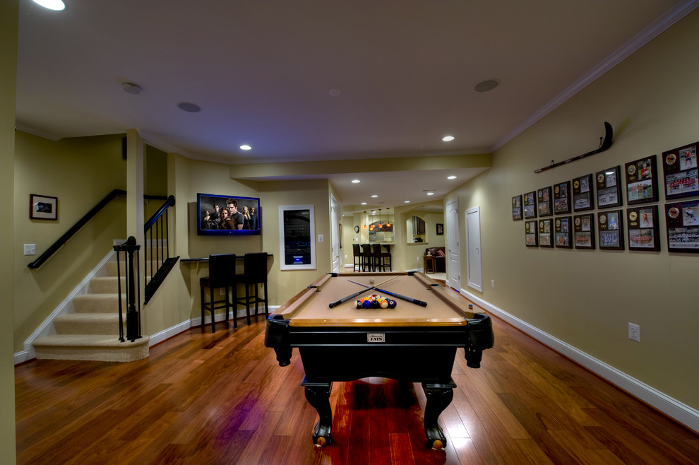 Expansive contemporary fully buried basement in DC Metro with yellow walls, medium hardwood flooring and brown floors.