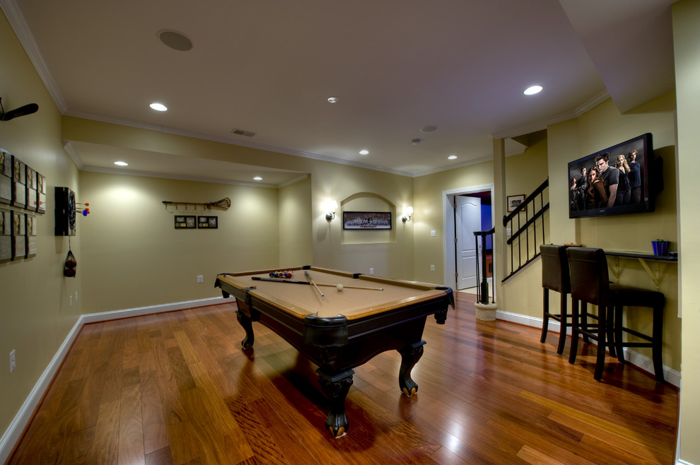 Expansive contemporary fully buried basement in DC Metro with yellow walls, medium hardwood flooring and orange floors.