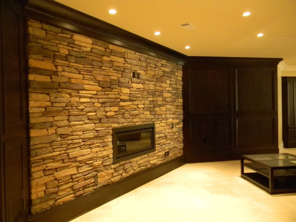 Cette image montre un grand sous-sol design enterré avec un mur beige, un sol en carrelage de céramique, une cheminée standard, un manteau de cheminée en pierre et un sol beige.