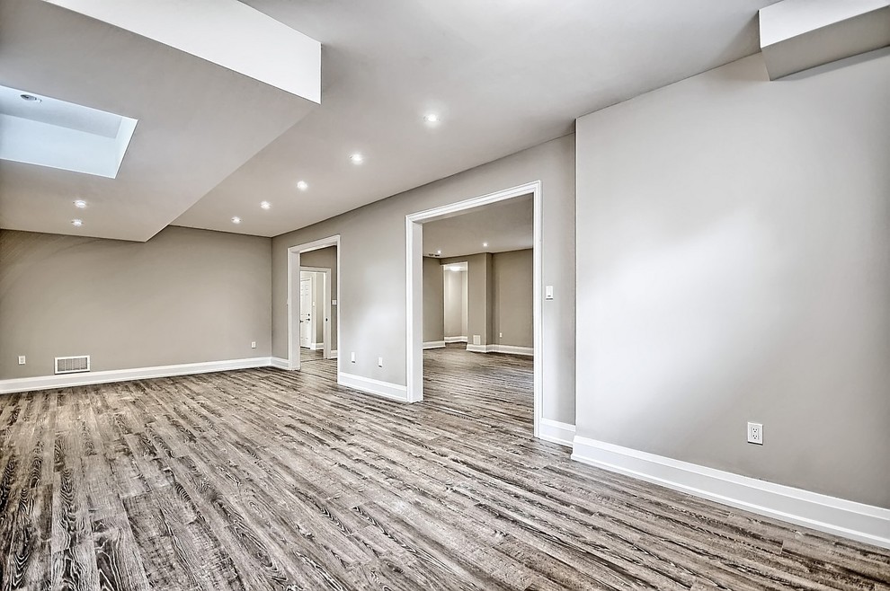 Großes Uriges Untergeschoss ohne Kamin mit grauer Wandfarbe, hellem Holzboden und beigem Boden in Toronto