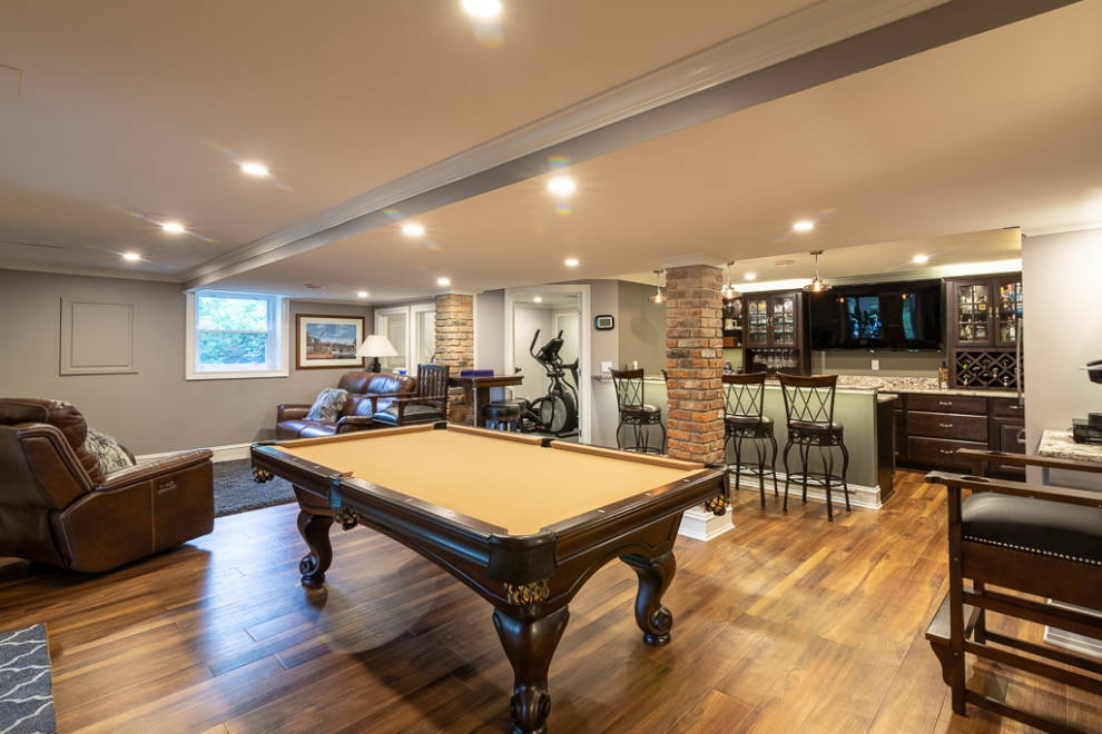 This is an example of a large classic walk-out basement in Chicago with grey walls, medium hardwood flooring, no fireplace and beige floors.