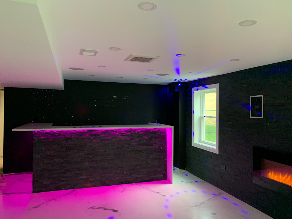 Cette image montre un sous-sol minimaliste semi-enterré et de taille moyenne avec un bar de salon, un mur noir, un sol en marbre, cheminée suspendue, un manteau de cheminée en pierre et un sol multicolore.