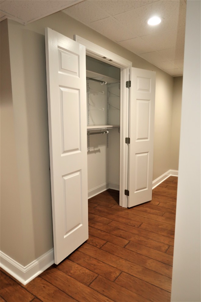 Aménagement d'un sous-sol classique donnant sur l'extérieur et de taille moyenne avec un mur gris, parquet clair et un sol marron.