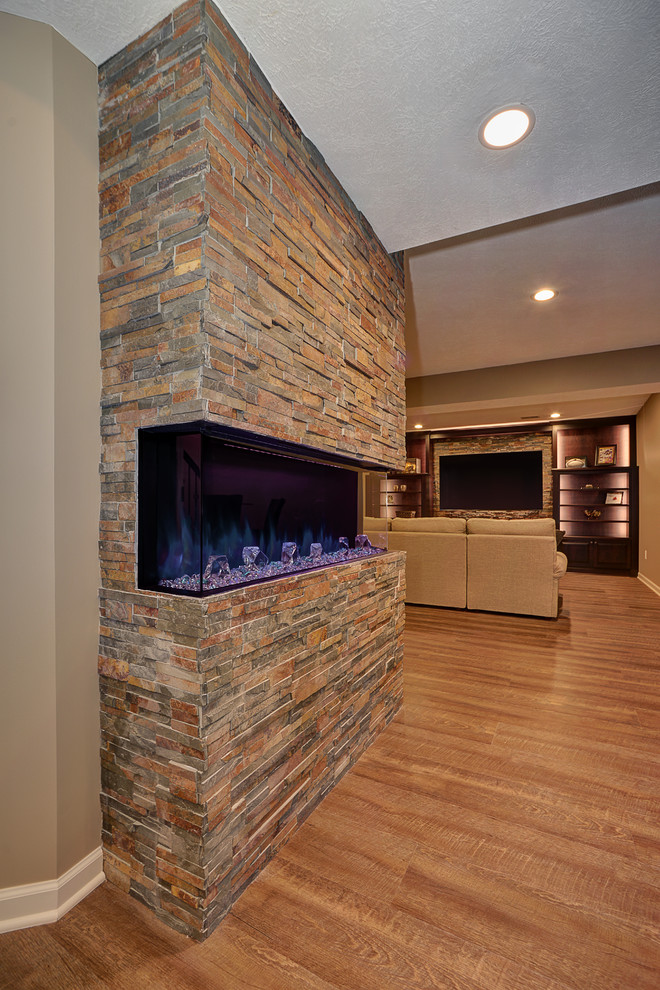 Example of a large classic underground medium tone wood floor and brown floor basement design in Other with beige walls, a ribbon fireplace and a stone fireplace