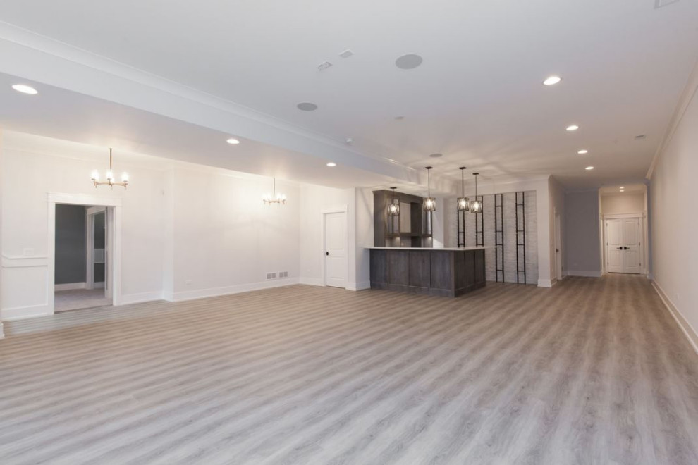 This is an example of a large farmhouse basement in Chicago with a home bar, white walls, light hardwood flooring and grey floors.