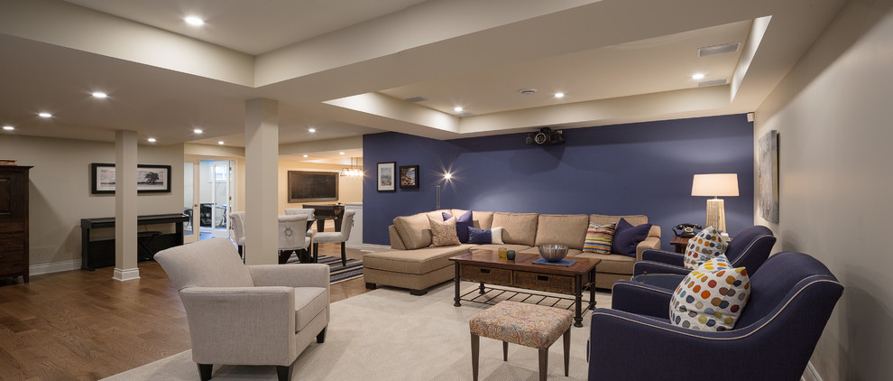 This is an example of a large beach style fully buried basement in Ottawa with blue walls, medium hardwood flooring and no fireplace.