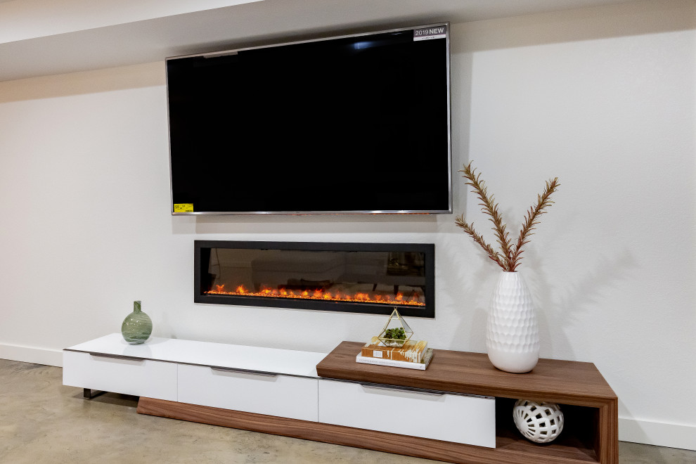 Example of a mid-sized minimalist underground concrete floor basement design in Other with white walls and a standard fireplace
