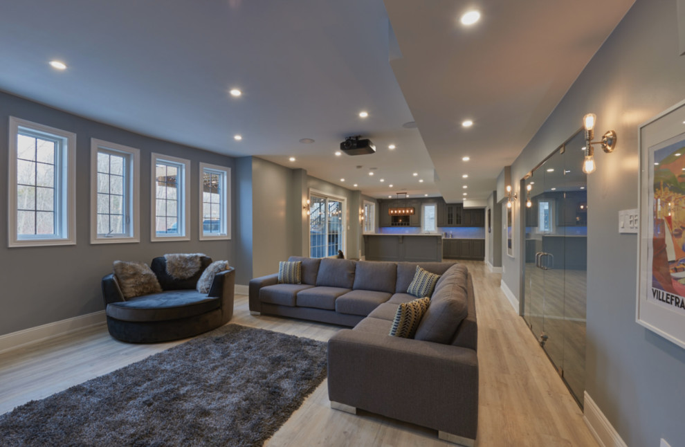 Design ideas for a traditional walk-out basement in Toronto with grey walls, light hardwood flooring, a ribbon fireplace and a stone fireplace surround.