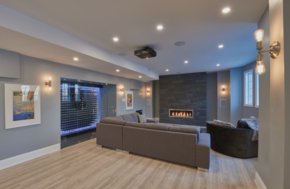 Inspiration for a classic walk-out basement in Toronto with grey walls, light hardwood flooring, a ribbon fireplace and a stone fireplace surround.