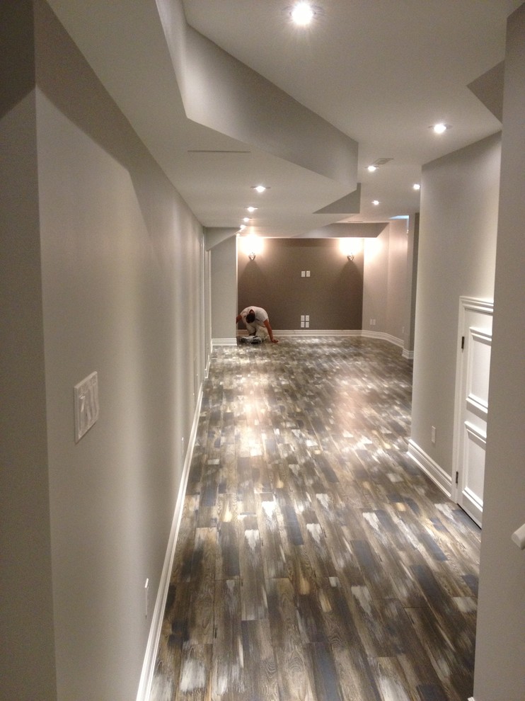 Mittelgroßes Modernes Souterrain ohne Kamin mit beiger Wandfarbe und braunem Holzboden in Toronto