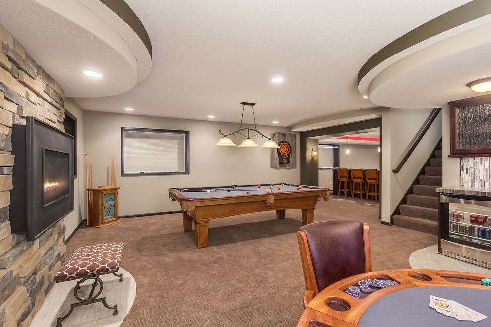 Example of a mid-sized transitional look-out carpeted and brown floor basement design in Minneapolis with beige walls, a standard fireplace and a stone fireplace