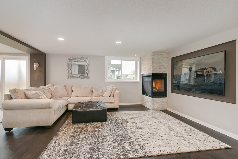 Large classic walk-out basement in Minneapolis with grey walls, dark hardwood flooring, a corner fireplace, a tiled fireplace surround, brown floors and a chimney breast.