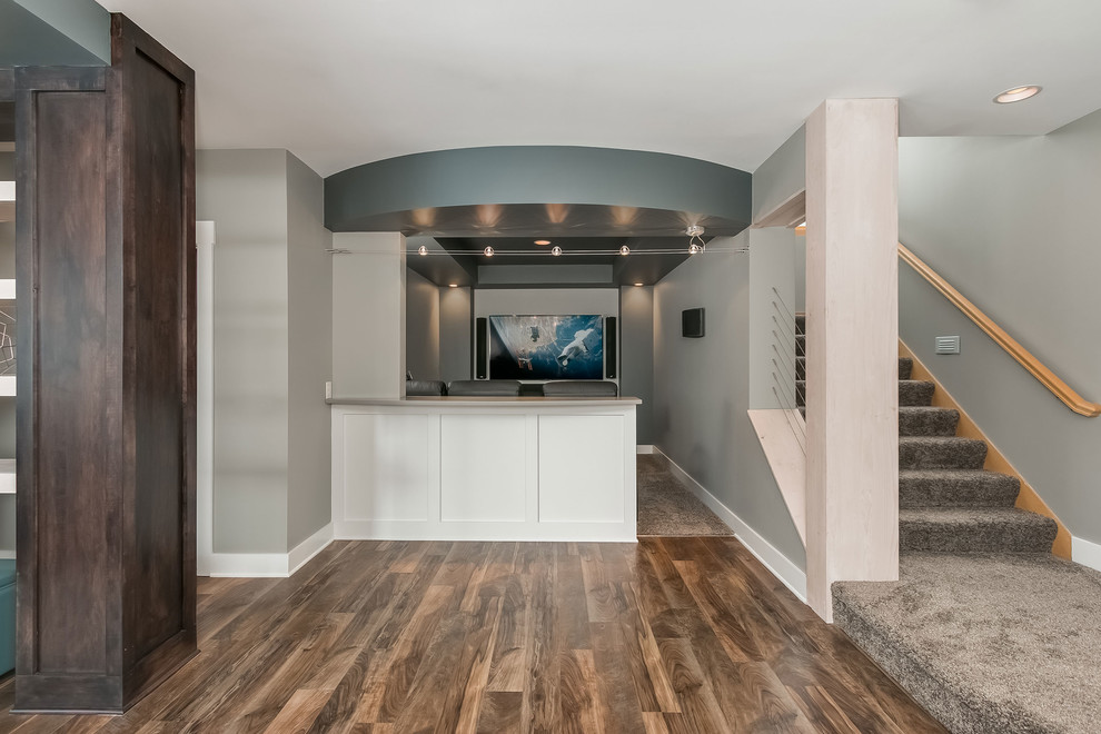 Geräumiger Moderner Hochkeller ohne Kamin mit grauer Wandfarbe, braunem Holzboden und braunem Boden in Minneapolis