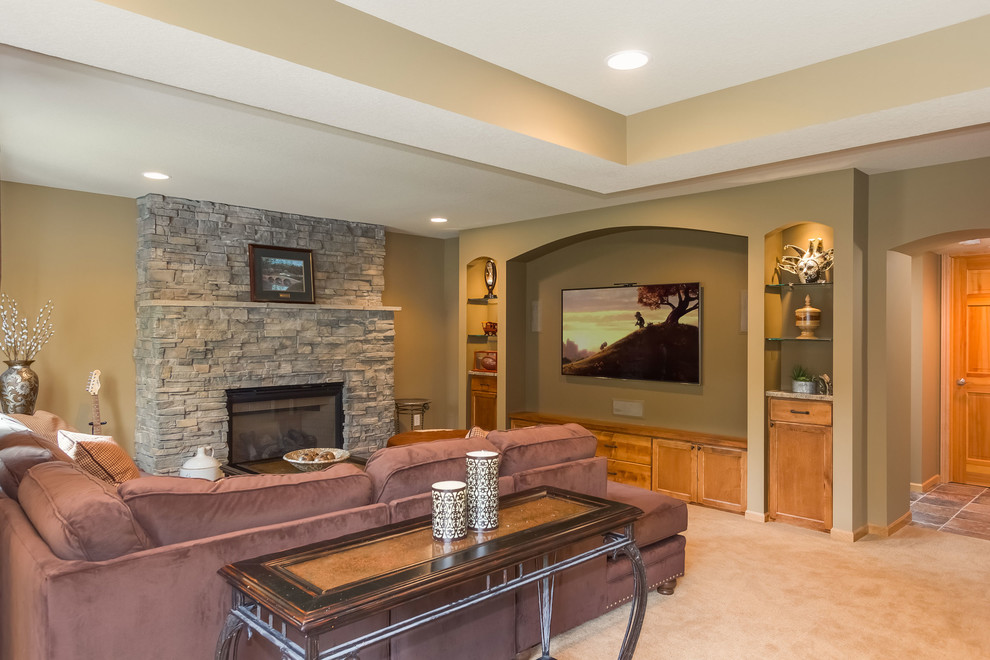 This is an example of a large traditional walk-out basement in Minneapolis with beige walls, carpet, a standard fireplace, a stone fireplace surround and beige floors.