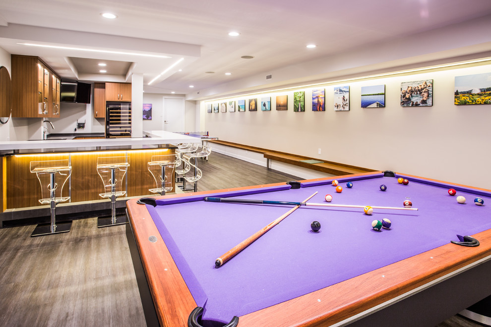 Basement game room - large modern underground dark wood floor and brown floor basement game room idea in New York with beige walls and no fireplace
