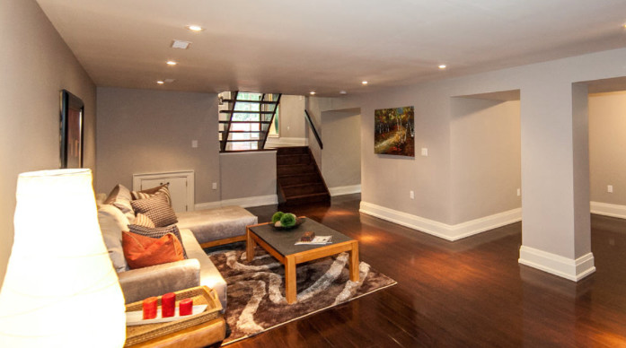 Example of a large trendy look-out dark wood floor and brown floor basement design in Toronto with beige walls and no fireplace