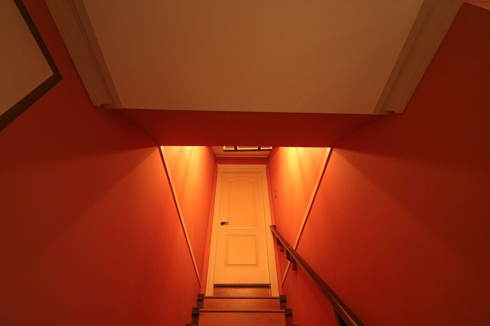 Пример оригинального дизайна: подземный подвал среднего размера в стиле неоклассика (современная классика) с оранжевыми стенами, паркетным полом среднего тона, стандартным камином, фасадом камина из камня и коричневым полом