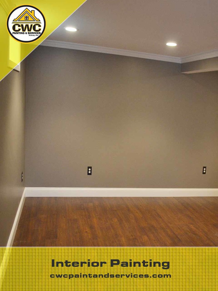 Large classic fully buried basement in Boston with grey walls, dark hardwood flooring and no fireplace.