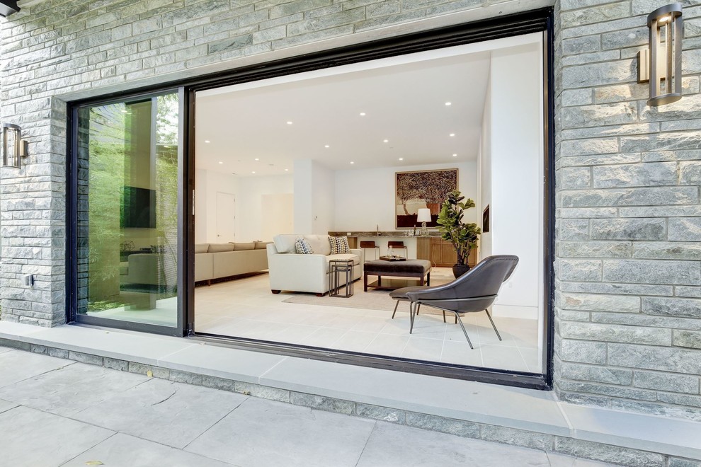 Photo of a large contemporary walk-out basement in DC Metro with white walls, limestone flooring, a standard fireplace, a stone fireplace surround and beige floors.