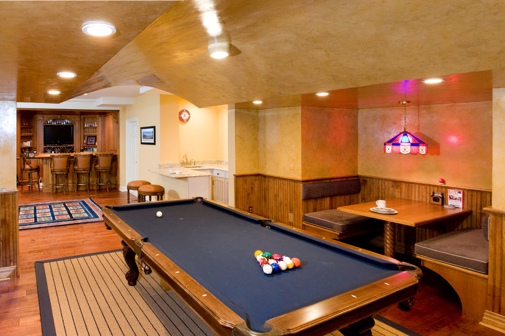 Immagine di un'ampia taverna classica interrata con pareti beige, pavimento in legno massello medio e pavimento arancione
