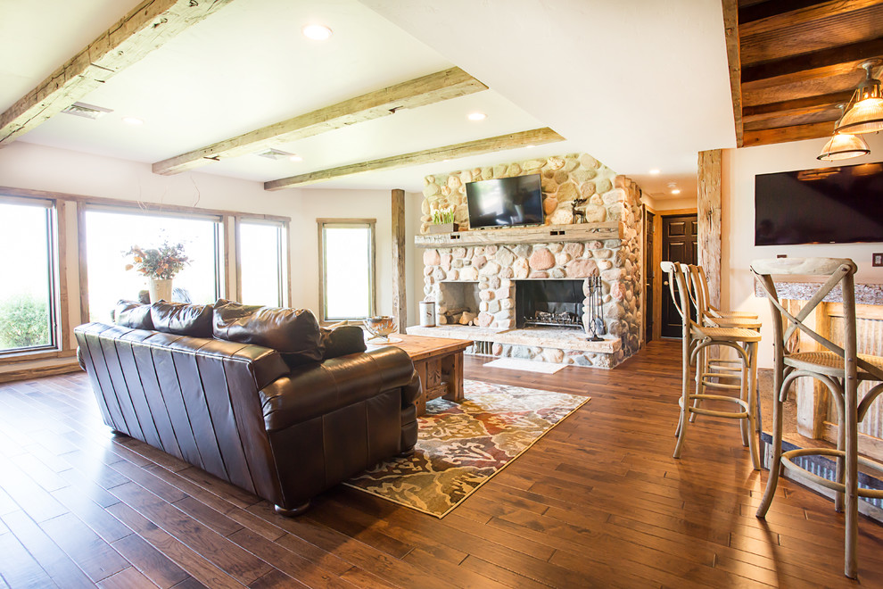 Large rustic walk-out basement in Other with white walls, dark hardwood flooring, a standard fireplace and a stone fireplace surround.