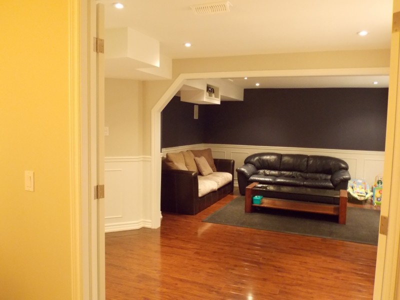 This is an example of a large classic look-out basement in Toronto with beige walls, medium hardwood flooring and a dado rail.