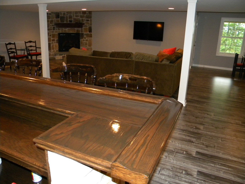 Example of a mountain style walk-out dark wood floor basement design in Philadelphia with gray walls, a standard fireplace and a stone fireplace