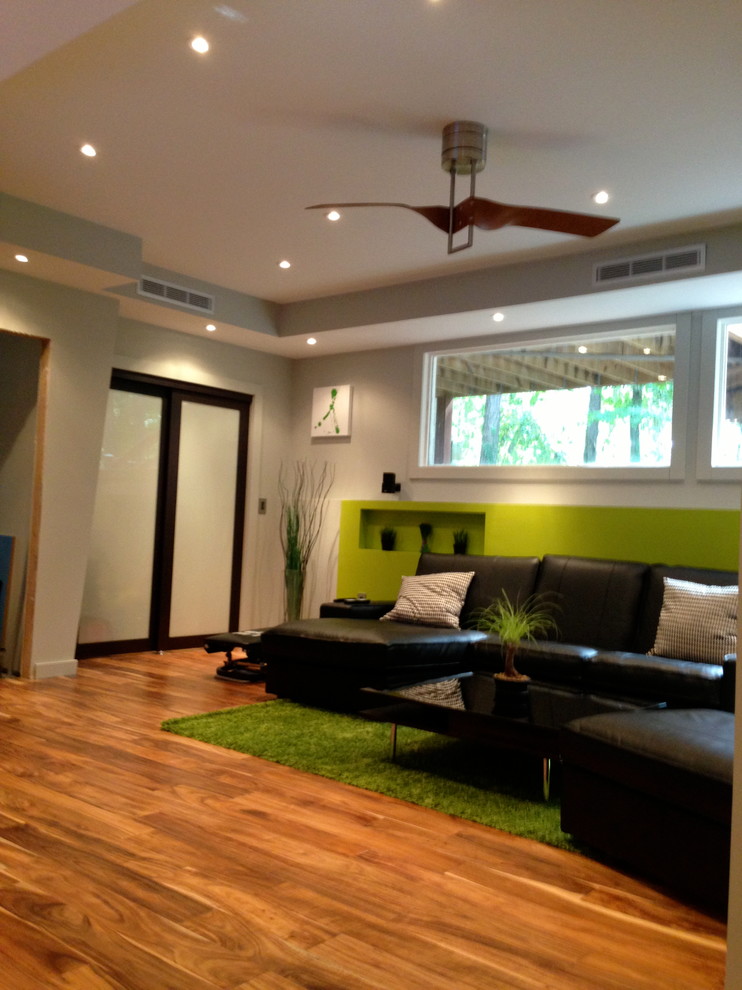 Réalisation d'un salon design avec un mur vert, un sol en bois brun et un sol orange.