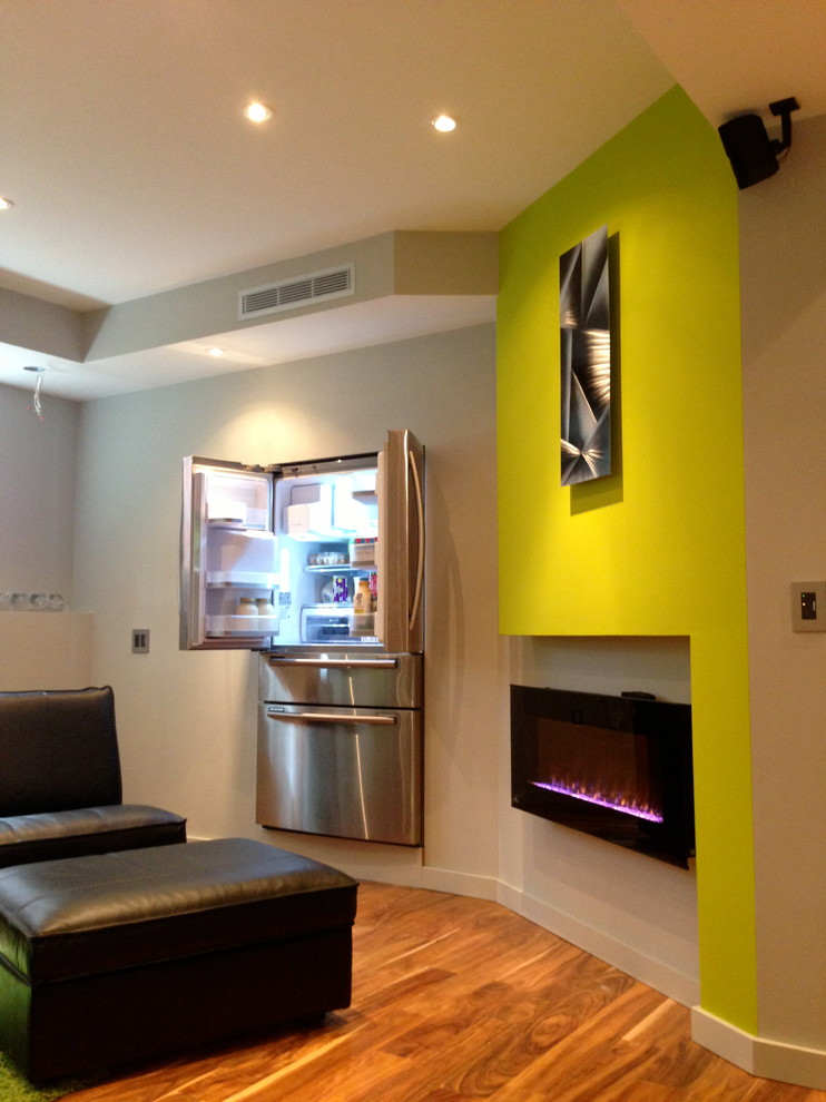 Cette image montre un sous-sol design avec un mur vert, un sol en bois brun et une cheminée ribbon.