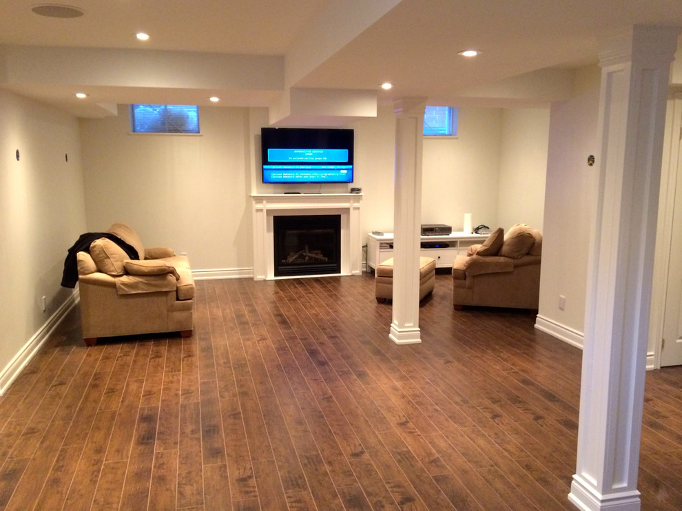 Inspiration for a mid-sized timeless underground medium tone wood floor basement remodel in Toronto with beige walls and a standard fireplace