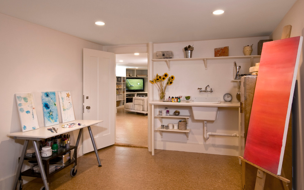 This is an example of a contemporary look-out basement in Boston with white walls and cork flooring.
