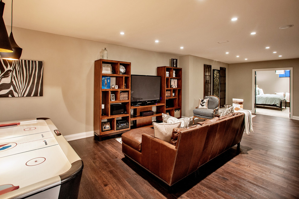 Design ideas for a large contemporary fully buried basement in Toronto with beige walls, dark hardwood flooring and no fireplace.