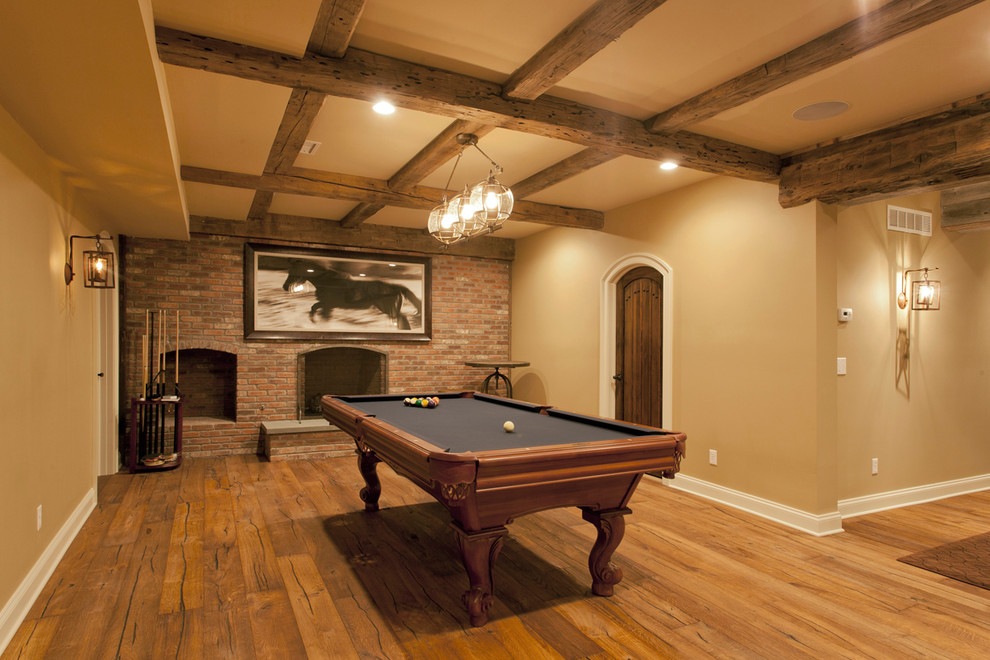 Large rustic fully buried basement in New York with beige walls, medium hardwood flooring, a standard fireplace and a brick fireplace surround.