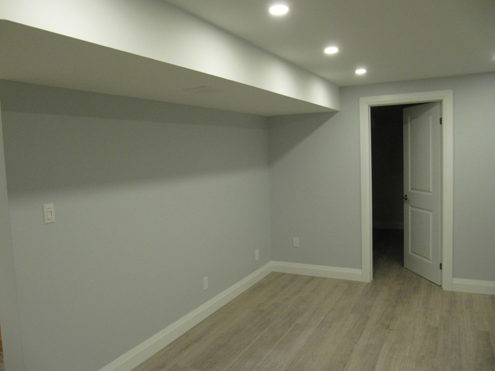 Example of a large minimalist underground laminate floor and gray floor basement design in Toronto with gray walls, a standard fireplace and a tile fireplace