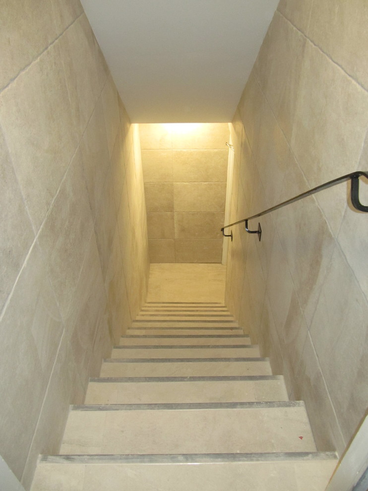 Diseño de sótano en el subsuelo moderno grande con paredes grises, suelo laminado, todas las chimeneas, marco de chimenea de baldosas y/o azulejos y suelo gris