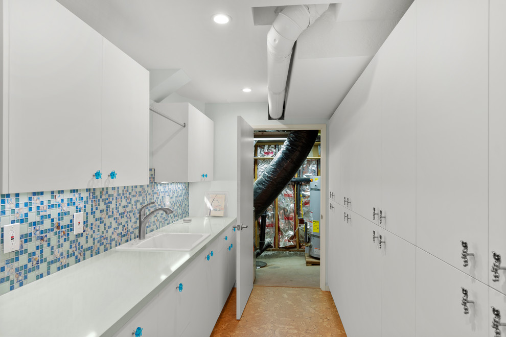 This is an example of an eclectic fully buried basement in San Francisco with white walls, cork flooring and brown floors.
