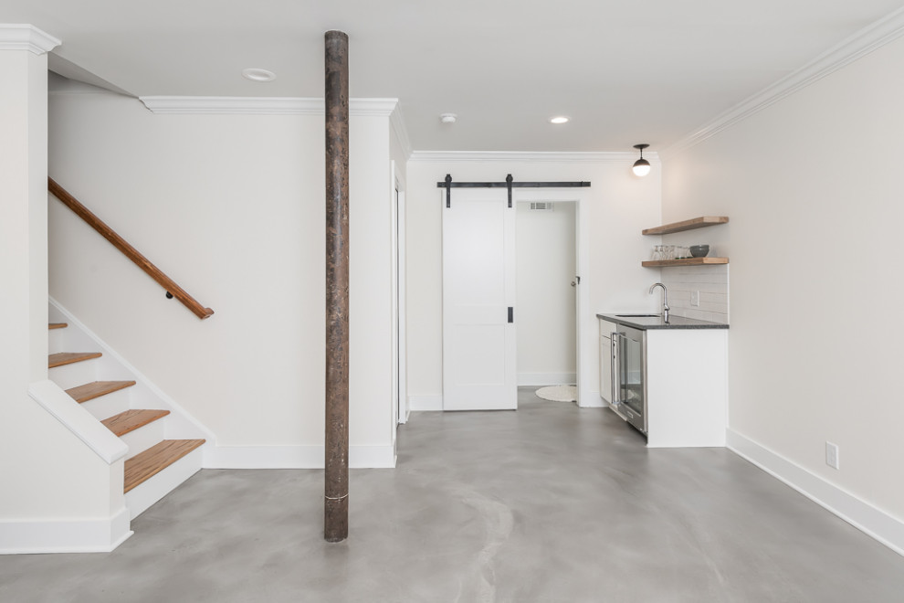 Imagen de sótano en el subsuelo minimalista de tamaño medio con paredes blancas, suelo de cemento y suelo gris