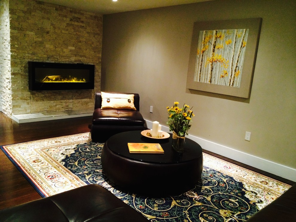 Inspiration for a large contemporary walk-out basement in Toronto with beige walls, dark hardwood flooring, a stone fireplace surround, a standard fireplace and brown floors.