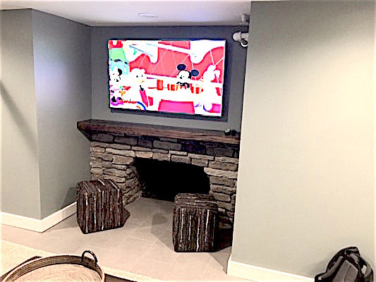 Foto på en stor funkis källare ovan mark, med grå väggar, klinkergolv i porslin, en standard öppen spis, en spiselkrans i sten och grått golv