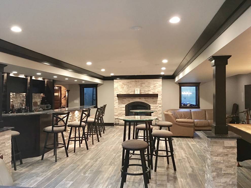 Basement - mid-sized transitional underground dark wood floor and brown floor basement idea in Chicago with beige walls, a standard fireplace and a stone fireplace